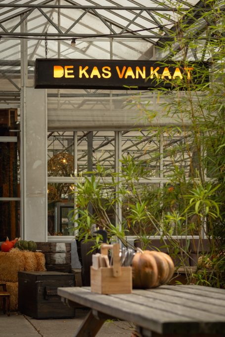 Uitzicht op de inrichting van een kas met het bord "De Kas van Kaat".