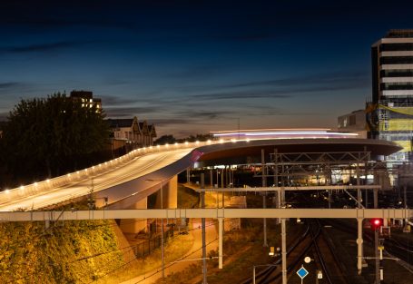Landschap met een spoorwegviaduct, bij nacht met bewegende lichten.