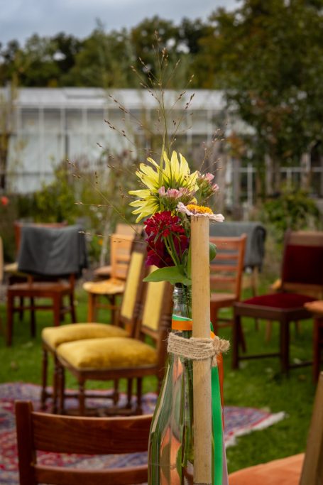 Een gezellige buitenruimte met stoelen en een bloemstuk in een vaas.