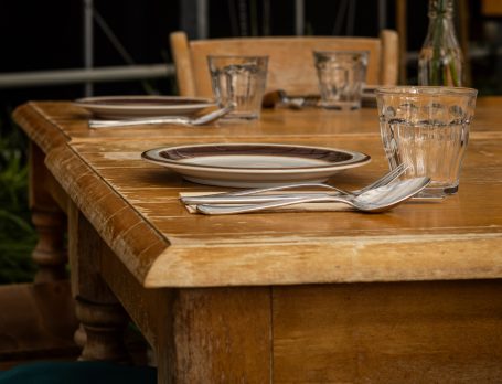 Houten tafel met een bord, bestek en glazen.